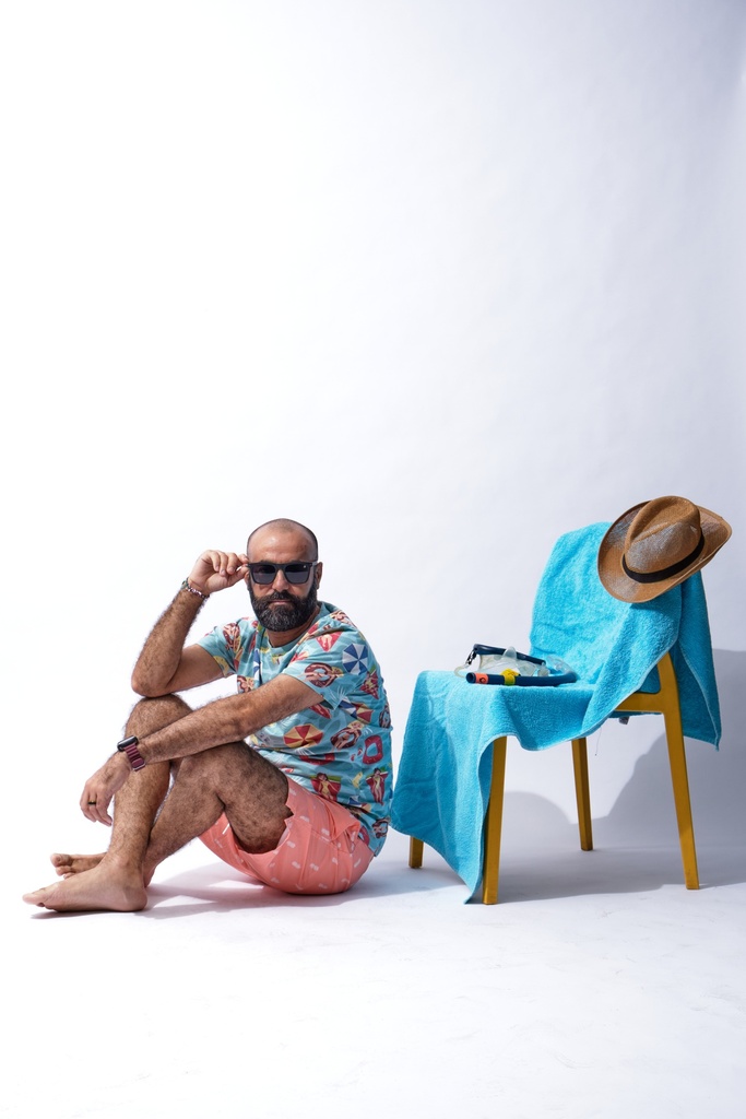 man on a beach fixing his eye glasses.