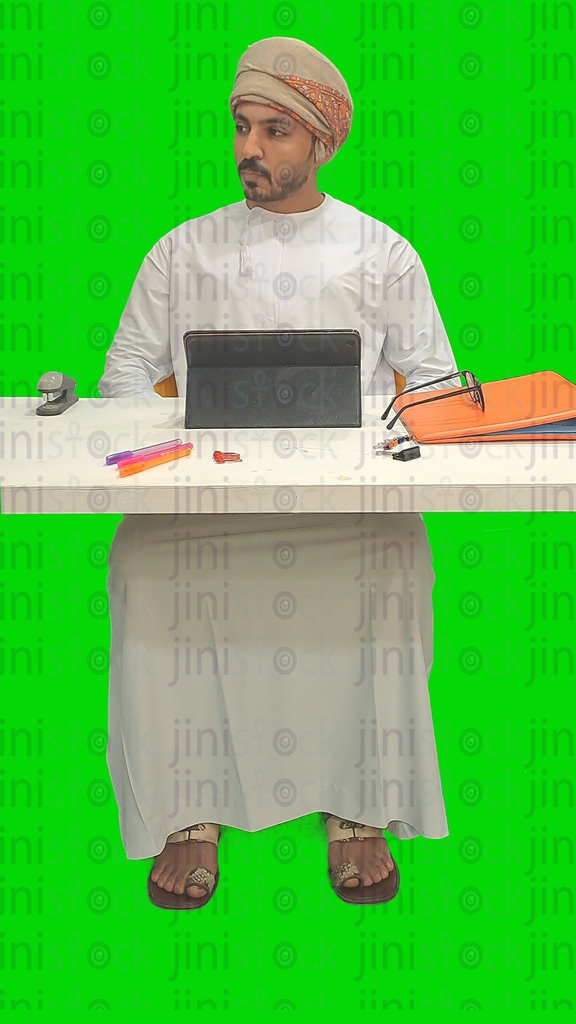 رجل عماني من الخليج يعمل على جهاز كمبيوتر لوحي في مكتبه