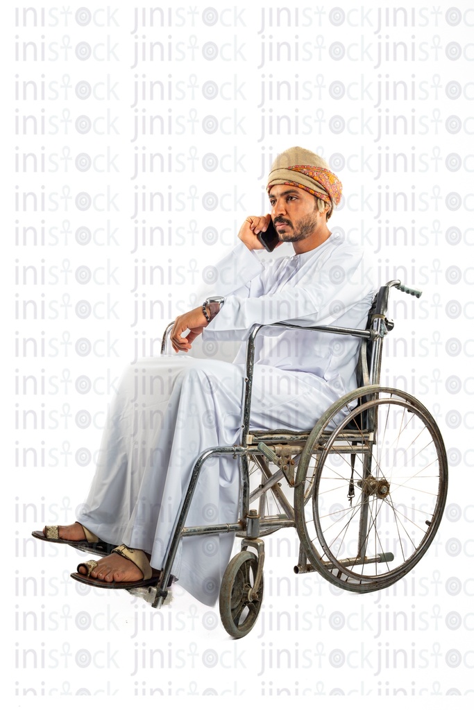 رجل عربي خليجي عماني من الخليج على كرسي متحرك يتحدث على الهاتف المحمول