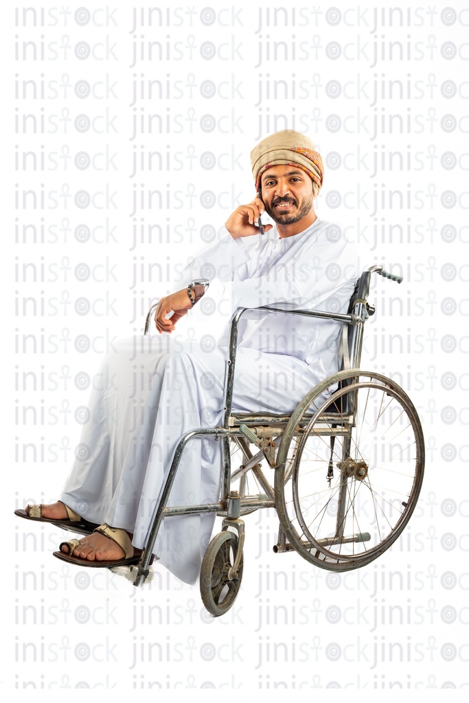 رجل خليجي عماني عربي من الخليج على كرسي متحرك يتحدث على الهاتف المحمول
