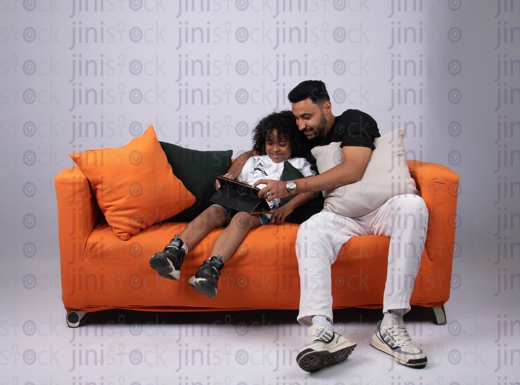 father son watching something on a couch