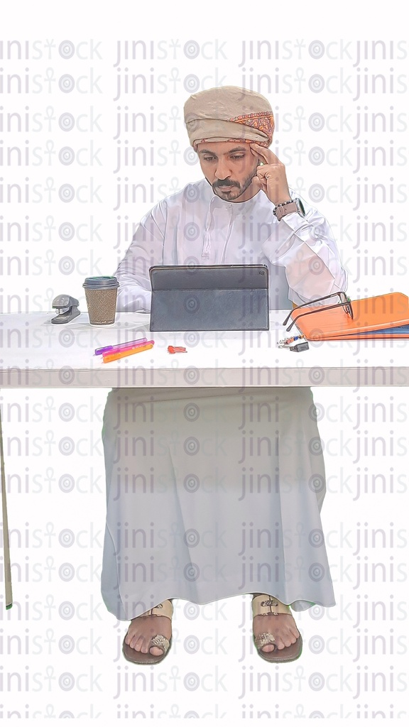Omani man from the Gulf working on a tablet in his office and thinking about something