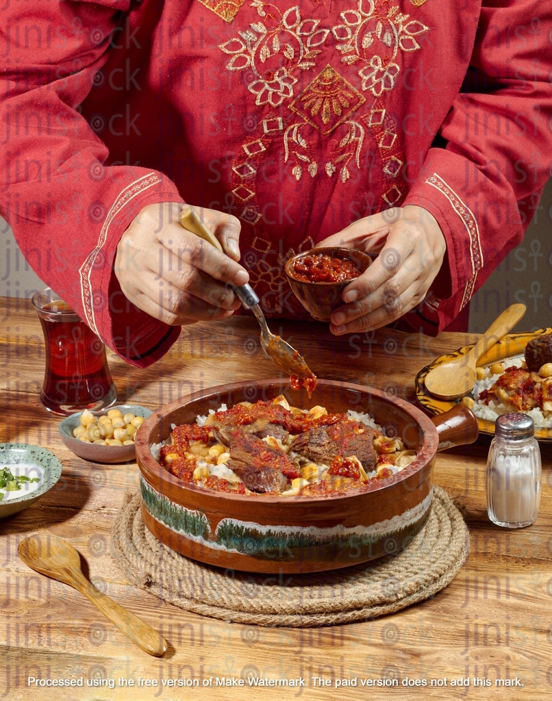 Woman adding tomato sauces to an Egyptian Fattah