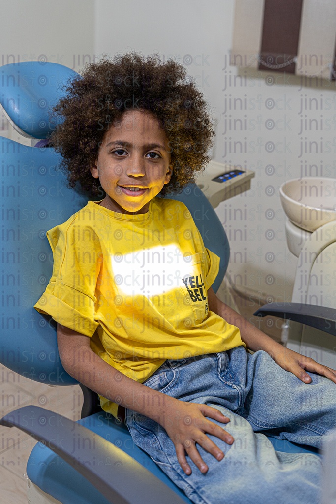 Little Egyptian boy with curly hair sitting on the dental chair