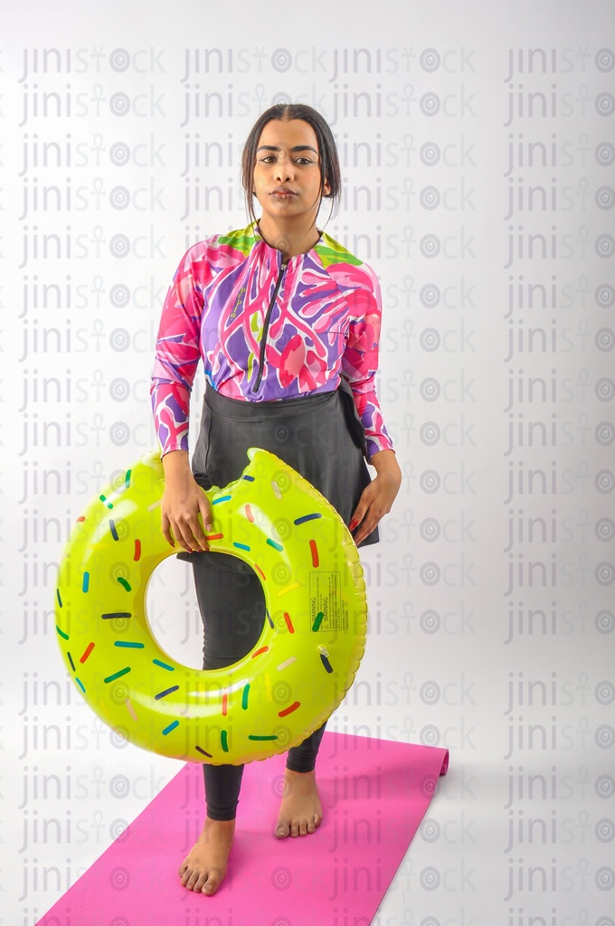 A girl wearing a burkini swimsuit and holding a float in her hand