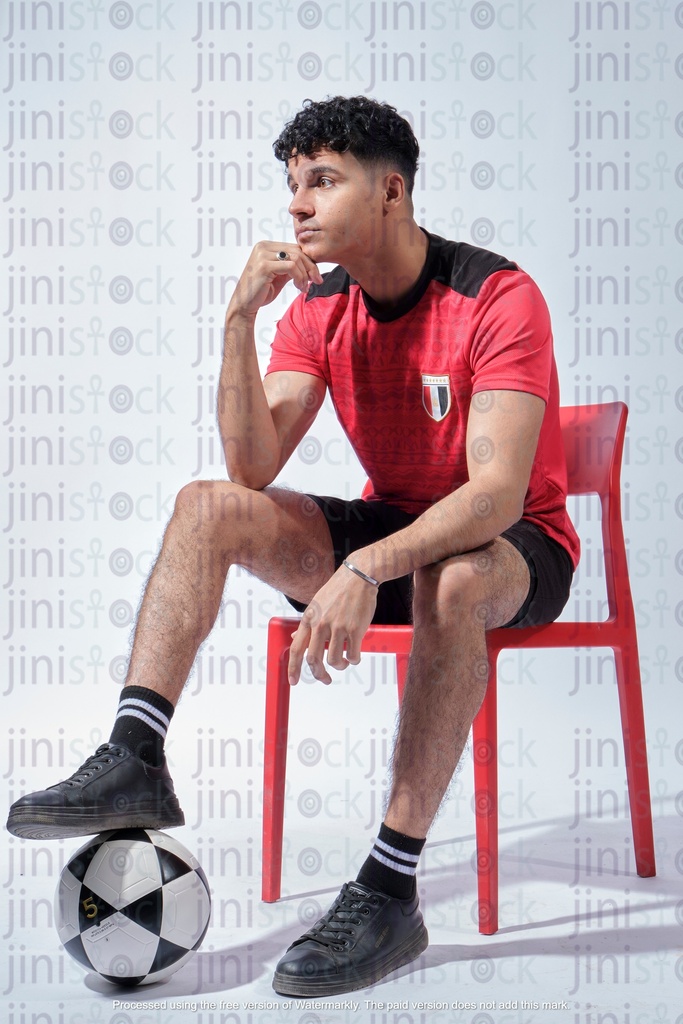 egyptian young man wearing el montakhab jersey shirt and his legs on the ball