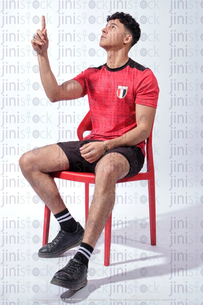 young egyptian man wearing the shirt of the Egyptian national football team and raising his hand