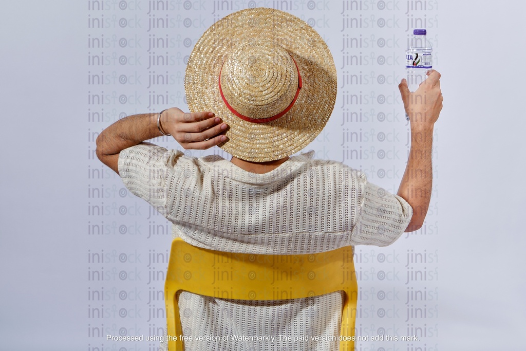 young egyptian man wearing a hat with his back to the camera and holding a bottle