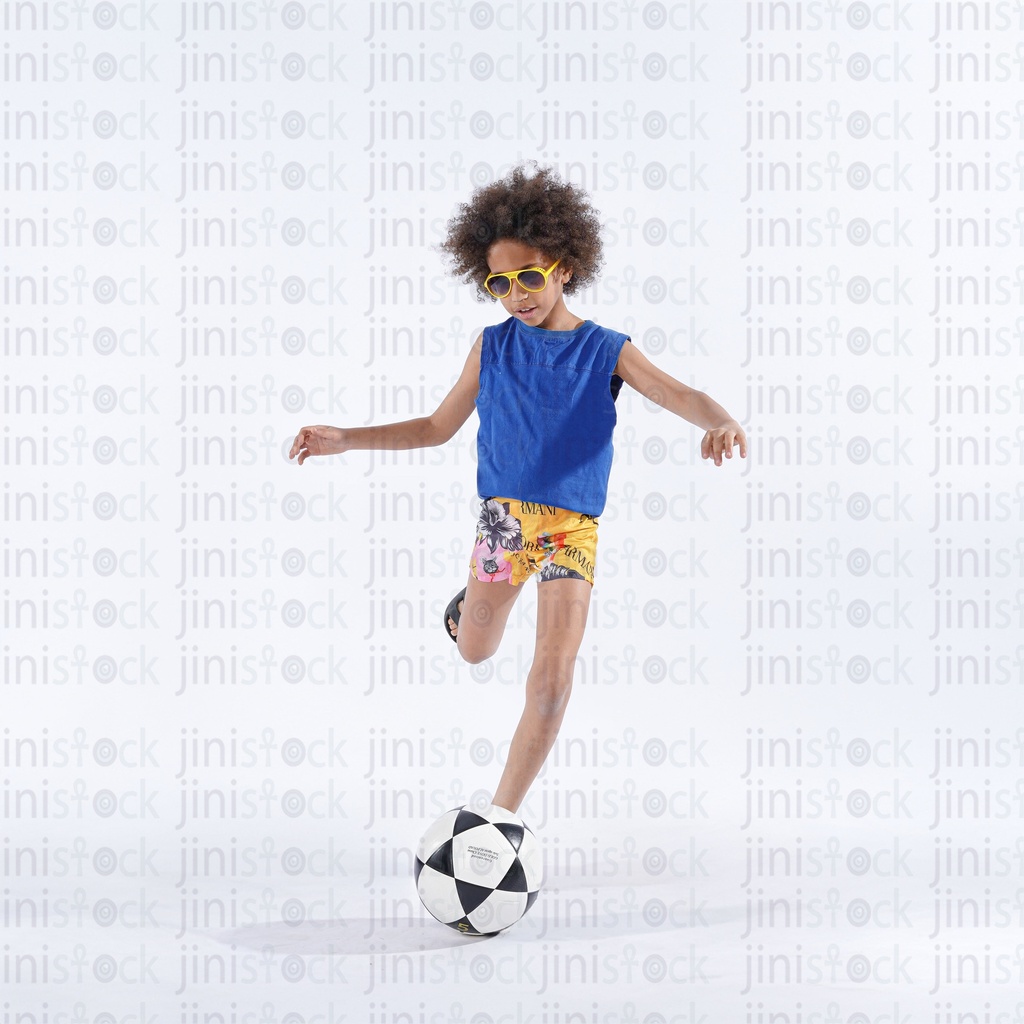 little boy with curly hair kicking football