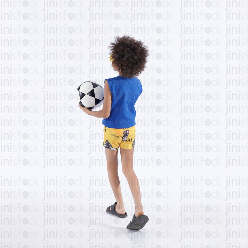 little boy with curly hair holding a football and his back to the camera