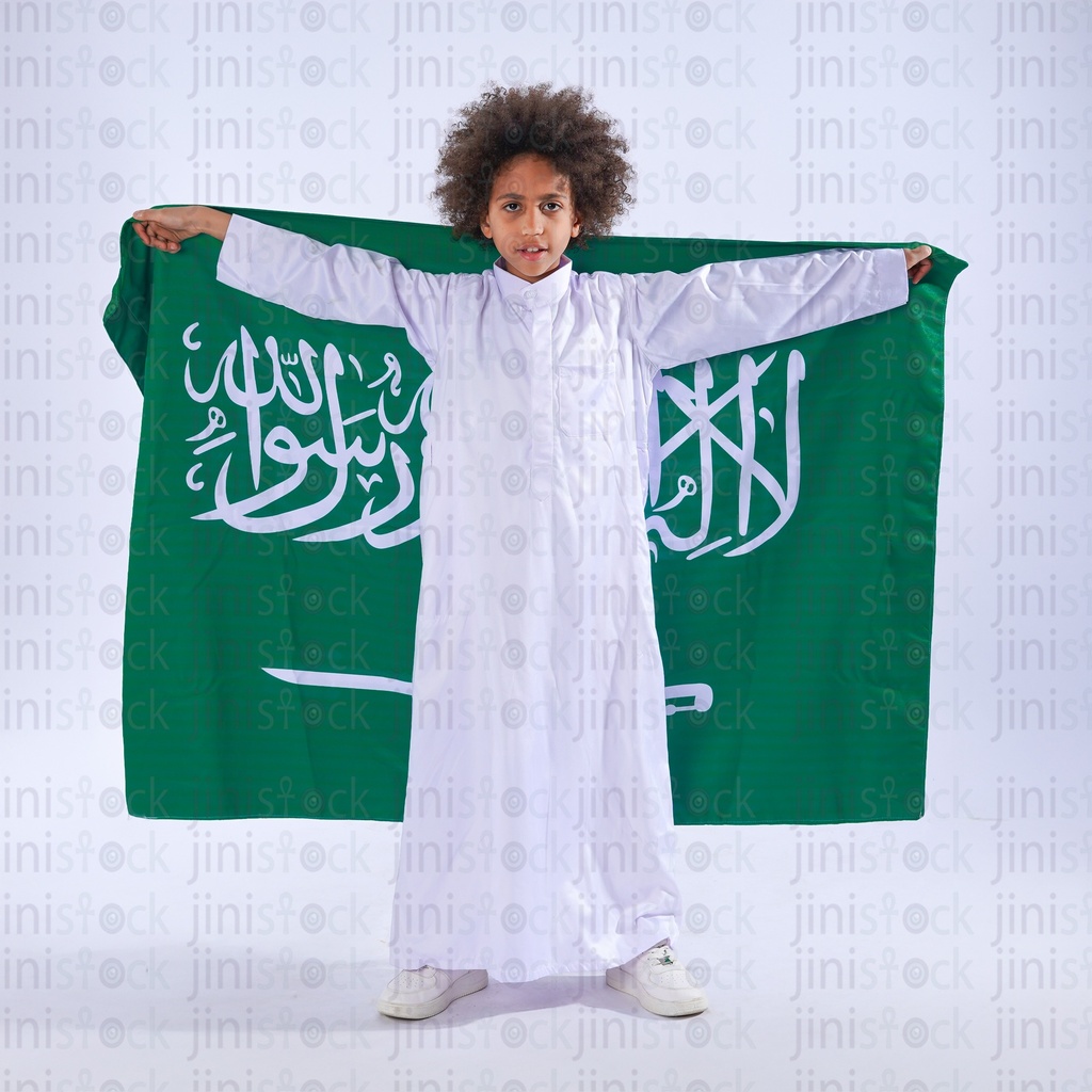 فتى سعودي من الخليج بشعر مجعد يحمل علم المملكة العربية السعودية