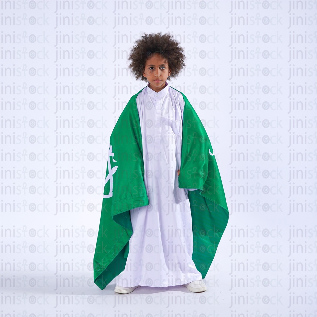 khaliji boy from saudi arabia holding the saudi flag over his shoulder