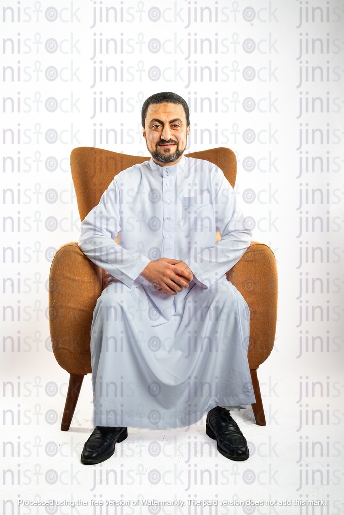 رجل سعودي خليجي من الخليج يجلس على كرسي وينظر إلى الكاميرا