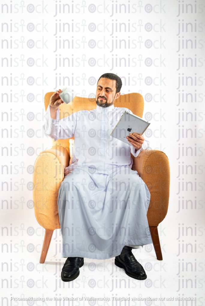 saudi khaliji man from gulf sitting on a chair holding  ipad on on hand and coffee mug on the other