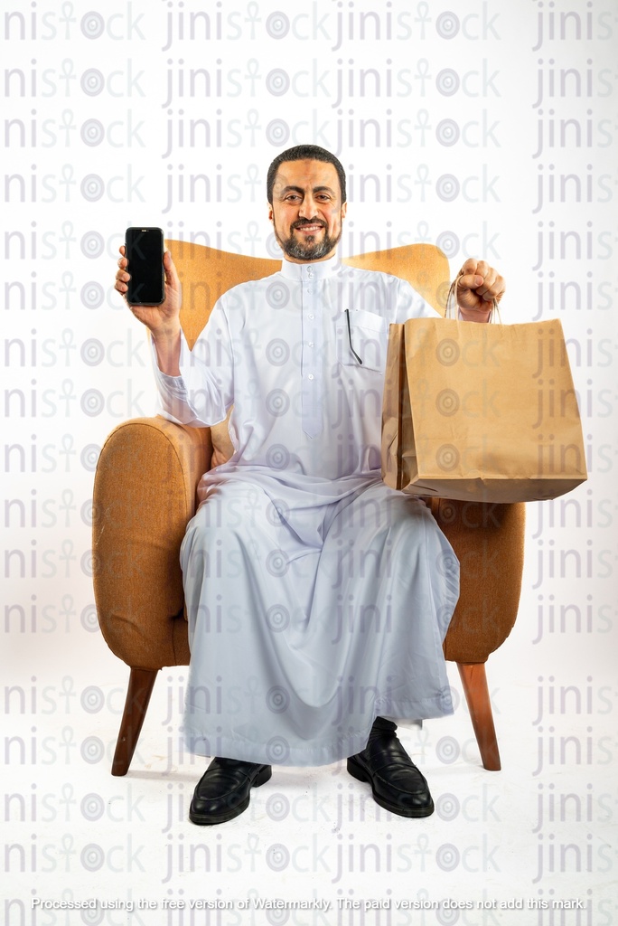 saudi khaliji man sitting on the chair holding a bag and a mobile phone