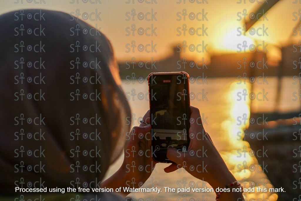 A girl takes a photo of the sunset with a felucca on the Nile