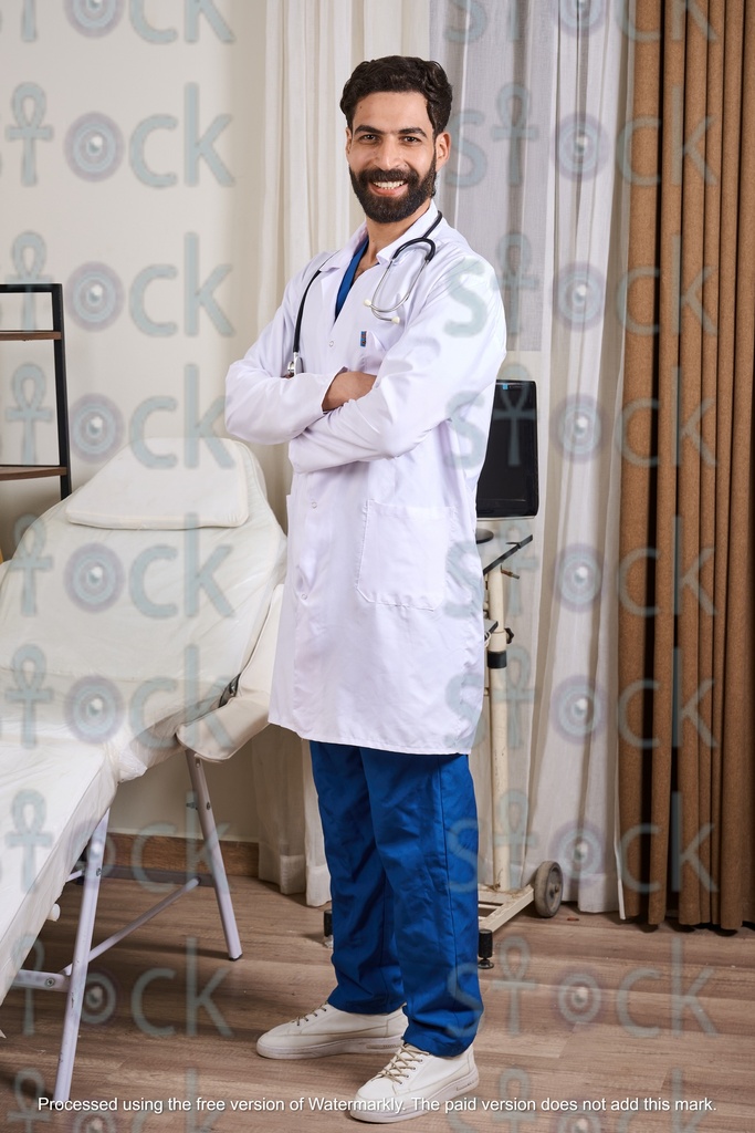 An Egyptian doctor standing in his clinic, smiling, wearing a medical coat and a stethoscope