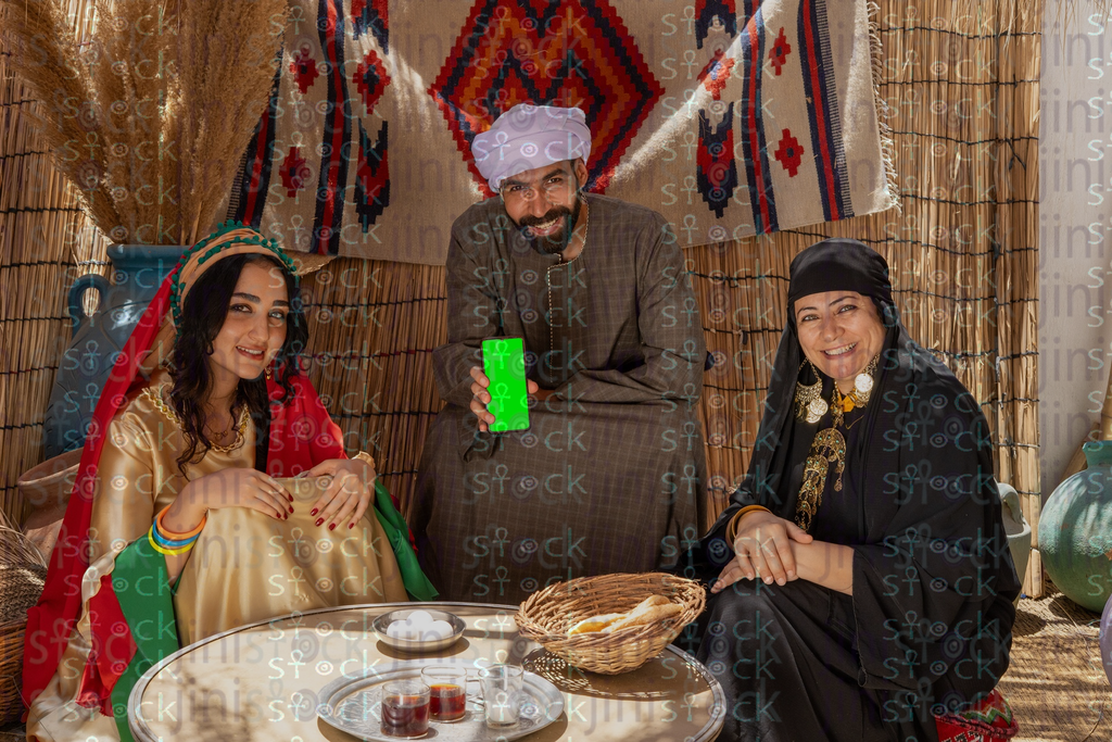 Young man sitting holding phone between a woman and a young woman