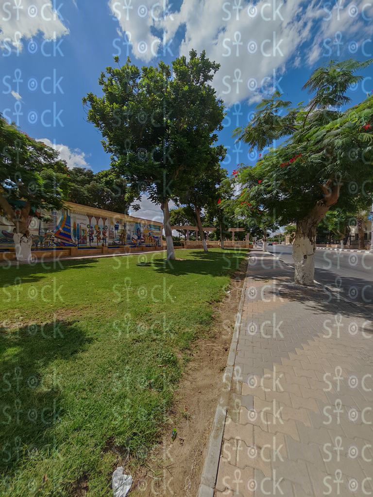 Benches next to a wall with pharaonic drawings surrounded by trees in Ismailia