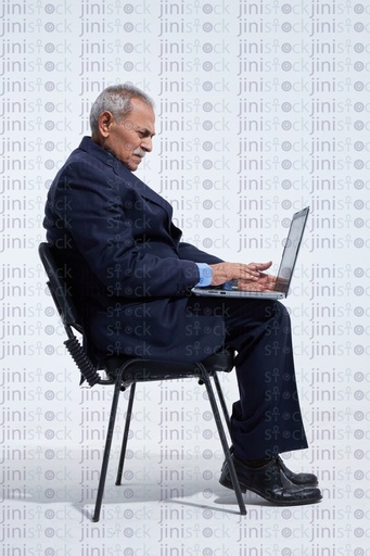 old man in a suite typing on a laptop or working