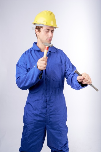 A worker wearing a blue uniform, working or hammering something.