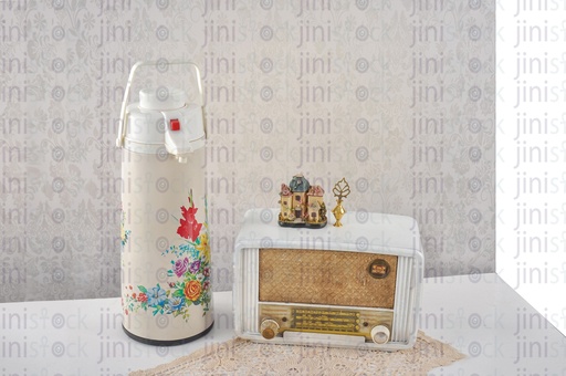 a vintage radio, home accessories, and kettle of tea on a table.