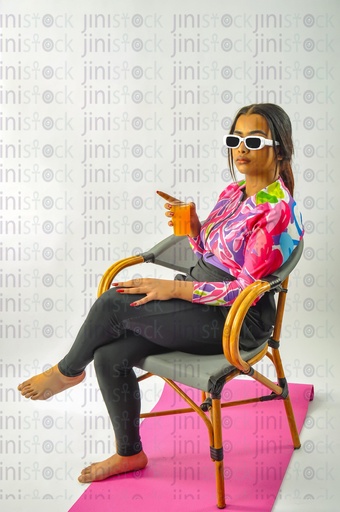 فتاة ترتدي ملابس السباحة البوركيني وتجلس على كرسي وتشرب عصير البرتقال