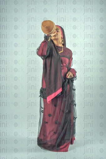 An Egyptian farmer girl or a Nubian Egyptian woman wearing Nubian clothes or a lady farmer drinking water from Qola