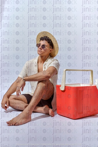 young Egyptian man Wearing sunglass and leaning on ice box on the beach