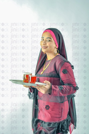 A Nubian Egyptian woman wearing a Nubian dress, a veil on her head, or an Egyptian farmer holding a tray of tea cups.