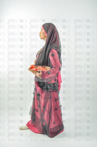 A farmer or a Nubian woman from Egypt wearing Nubian clothes and holding a plate of tomatoes in her hands