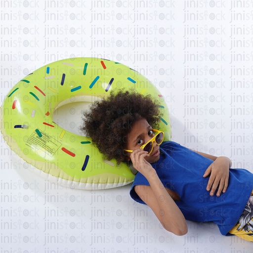 Little boy with curly hair laying on his back on a water float and wearing sunglasses