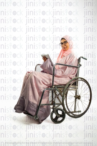 امرأة خليجية سعودية من الخليج على كرسي متحرك، معاقة وطالبة ترتدي نظارات وتحمل كتبًا أو دفتر ملاحظات.