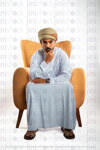 رجل عماني خليجي من الخليج يجلس على الكرسي ويركز على الكاميرا ويفكر قد يكون منزعجًا