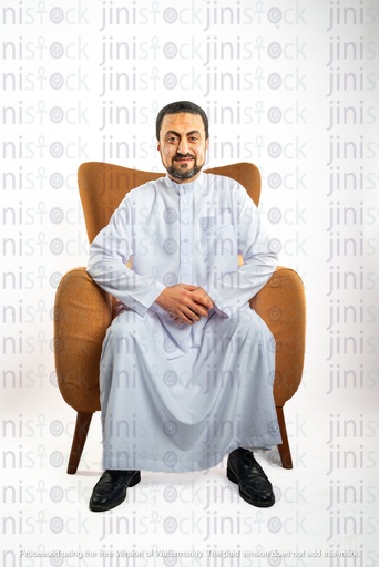 رجل سعودي خليجي من الخليج يجلس على كرسي وينظر إلى الكاميرا