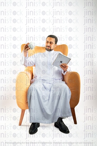 saudi khaliji man from gulf sitting on a chair holding  ipad on on hand and coffee mug on the other