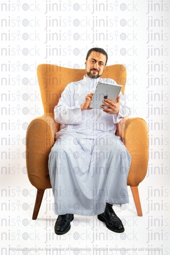saudi khaliji man sitting on the chair scrolling on his ipad