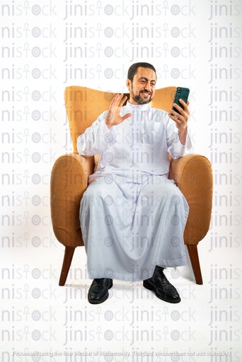saudi khaliji man sitting on a chair waving during a video call on his mobile