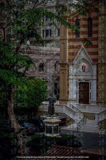 an ancient egyptian church or cathedral building with a distintctive architecural style, with a fountain and green trees next to it