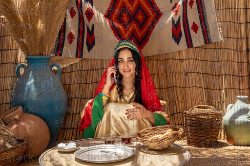 Egyptian peasant woman sitting in a hut talking on the phone 