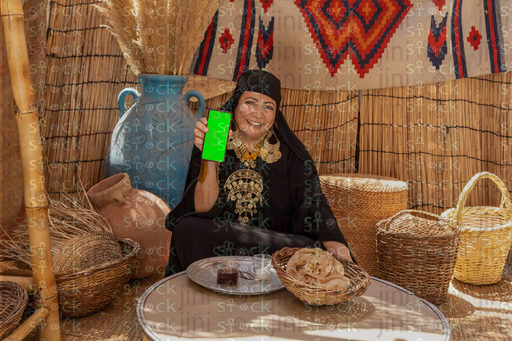 Egyptian woman sitting holding a phone with a green screen