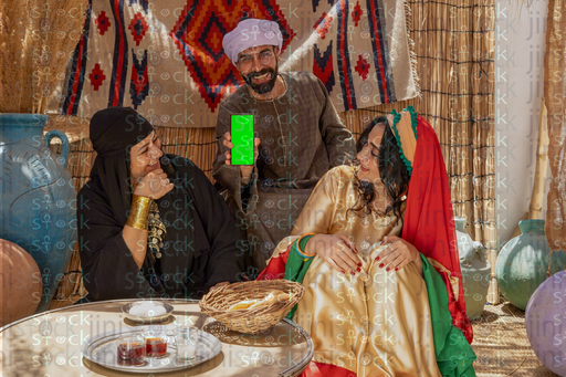  شاب يجلس بين امراة وشابة ينظرون الى الهاتف ضاحكين