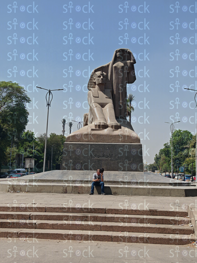 A person resting on the stairs in front of the statue